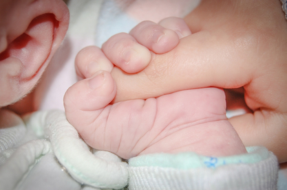 Babyhånd holder om voksens finger